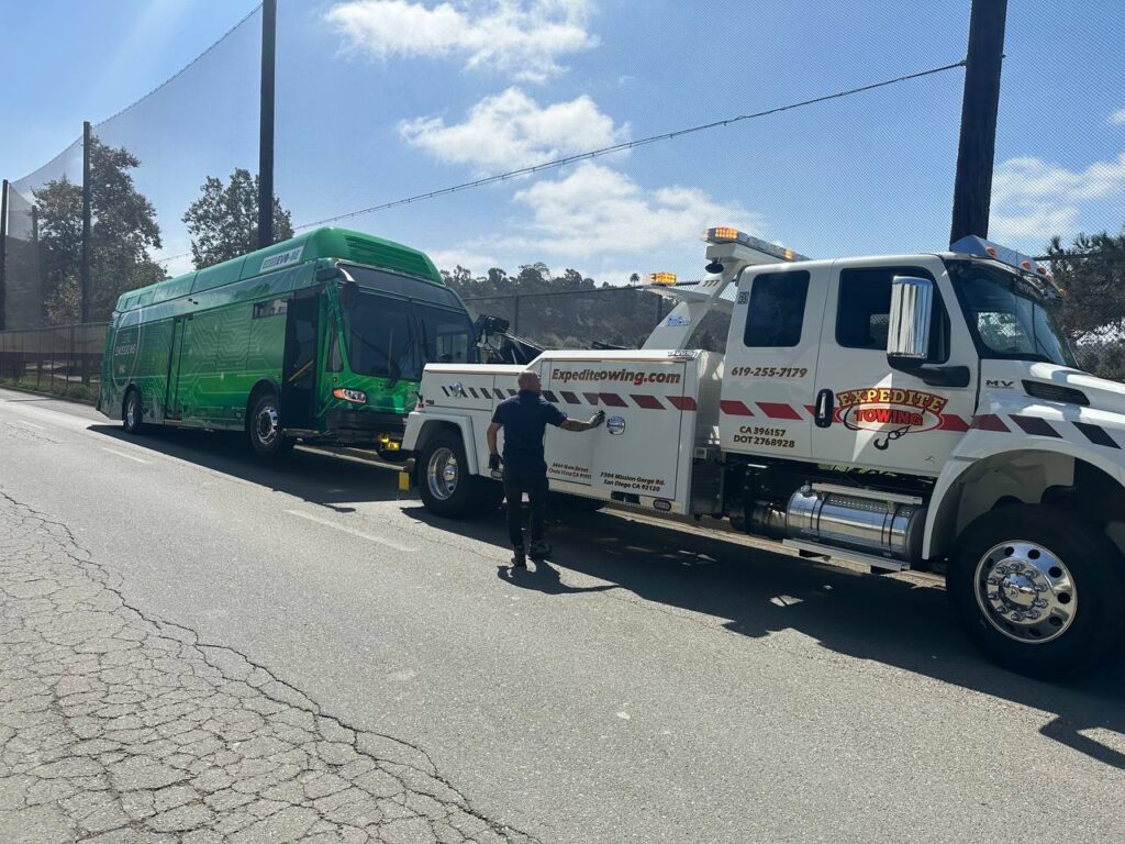 Heavy-duty tow truck loading a vehicle onto its platform in San Diego, showcasing Expedite Towing's professional services.